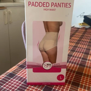 BYE BRA PADDED PANTIES HIGH WAIST L - Bye Bra vadderade trosor med hög midja ger dig ett vällustigt och krökt utseende. denna vadderade trosor är fylld med ett speciellt skum för en extra rundare och fylligare form. Den övre delen av de vadderade trosorna är gjord av ett mycket töjbart mikrot