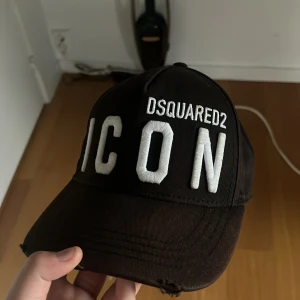 Icon dsquard 2 keps - Kepsen köptes i room 1006 på emporia för några månader sen och är ganska ny. Den är lite solblekt och den ska vara sönder så som den är på bilden. 