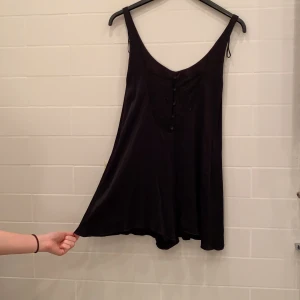 Svart romper med spets detaljer i ryggen - En fin svart romper från Zara med spets detaljer i ryggen med knappar, lite volanger vid benen