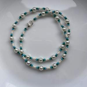 Ett halsband med lite större vita pärlor och blåa,gröna,beiga och vita pärlor💓