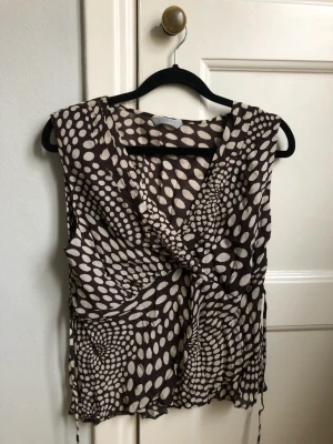 Mönstrat linne med snörning bak  - Söt brun/gräddvit topp utan ärmar med coolt mönster. Snören för att knyta där bak eller fram. Frakt 30 kr😽