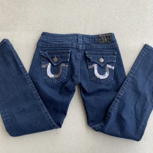True Religion Jeans - Jeans från true religion storlek 26, väldigt korta på mig som är 173. skulle säga att storleken motsvarar xs. modellen är billie straight. MÅTT: midjemått rakt över: 33cm, innerbenslängd: 70 cm, låret rakt över: 23cm. är bortrest, skickad tidigast 23/2