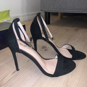 Svarta sammet klackar - Svarta sammets klackar som har öppen tå och spänne runt fotleden. Ca 10cm klack. Säljer då de inte passar mig. Aldrig använda.