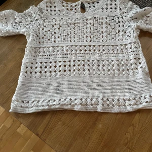 Vit virkad blus från Peppercorn - Superfin vit blus från Peppercorn i virkad stil med genombrutet mönster. Långärmad och med rund halsringning, perfekt för vår och sommar. Snyggt detaljerad och luftig, passar till både jeans och kjol.