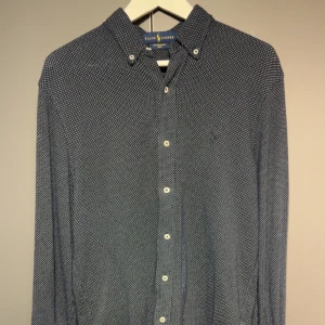Mörklblå skjorta från Ralph Lauren - Säljer en mörkblå skjorta från Ralph Lauren. Säljer denna för att den ej passar längre, väldigt bra skick bara använd ett fåtal gånger. Hör av dig vid minsta fundering!