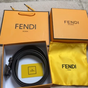 Fendi svart bälte med FF-logo - Snyggt svart bälte från Fendi med ikoniskt FF-mönster i mörka toner och stor metallspänne med Fendi-logga. Bältet är gjort i skinn och har exklusiv känsla, perfekt för att lyfta din outfit med en lyxig touch.