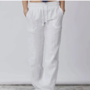 Vita linnebyxor med resårmidja - Snygga och luftiga lågmidjade vita linnebyxor med resår i midjan och fickor framtill. Perfekta för varma dagar och ger en avslappnad vibe. Raka ben och enkel design som passar till det mesta. 