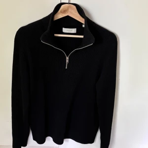 Svart stickad half zip från Jack & Jones - Svart ribbstickad tröja från Jack & Jones Premium med hög krage och half zip-dragkedja. Långärmad modell i mjuk stickad bomull, perfekt för lager-på-lager och chill höst- eller vinterstil.