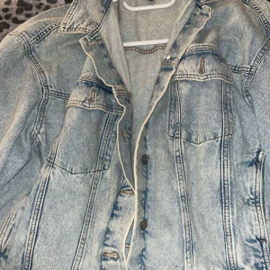 Oversized ljusblå jeansjacka Divided XL - Säljer en oversized ljusblå jeansjacka från Divided i storlek XL. Klassisk modell med knappar framtill, två bröstfickor och långa ärmar. Jackan har en avslappnad passform och är tillverkad i slitstarkt jeanstyg. Perfekt för en chill och trendig look.