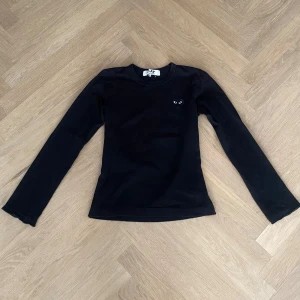 Svart långärmad tröja Comme des Garçons - Långärmad tröja från Comme des Garçons Play. Har sytt in midjan lite och även lagt ner ärmarna för att göra de lite längre. Går att sprätta upp sömmarna som jag sytt in för att göra tröjan till sin original storlek/passform. Strl M men passar mer en strl XS/S