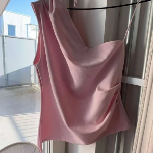 Ljusrosa oneshoulder linnetopp från gina tricot💞 - Säljer en superfin ljusrosa linnetopp med oneshoulder-design och tunn axelrem. Toppen har en snygg draperad effekt framtill och är perfekt för dig som gillar en stilren men trendig look. Aldrig använd!💞