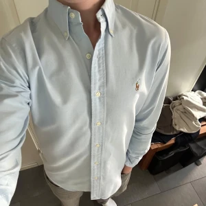 Ralph Lauren Skjorta - Ljusblå (Stl S) - Säljer denna sjukt snygga ljusblå skjorta från Ralph Lauren. Skjortan är i gott skick men har tyvvär fått en två fläckar på högra armen (bild 5) som kanske går bort i tvätt. För övrigt är skjortan i gott skick. Nypris ligger på 1600kr