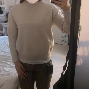 Beige stickad tröja från Gina Tricot -  Basic beige stickad tröja från Gina Tricot. Tröjan har rund halsringning, ribbade muddar och lång ärm. Perfekt att slänga på sig när det är kyligt ute. Enkel att matcha med allt och har en clean, avslappnad vibe.