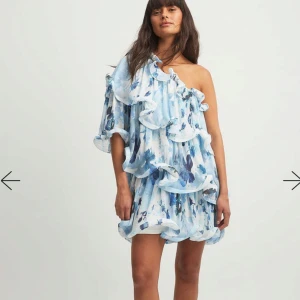 Slutsåld klänning från NAKD  - Superfin kort klänning med blått och vitt blommönster, volangdetaljer och oneshoulder-design. Säljer då jag inte får någon användning för den. Lapppen är kvar och den är aldrig använd!🩵