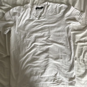 Vit v-ringad t-shirt från Size & Needle - Vit t-shirt från Size & Needle i storlek L. Klassisk v-ringning och korta ärmar, tillverkad i mjuk bomull. Enkel och clean design som passar perfekt till jeans eller shorts. Snygg basic som alltid funkar.