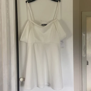 Vit offshoulder kortklänning Boohoo - Superfin vit kortklänning från Boohoo med offshoulder och smala axelband. Klänningen har en enkel, stilren design och är tillverkad i ett mjukt, slätt material som ger ett snyggt fall. Perfekt för dig som gillar minimalistisk och fräsch stil.