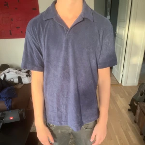 Blå frotté pikétröja - Säljer en blå pikétröja i mjuk frotté med klassisk krage och korta ärmar. Perfekt för dig som gillar en chill och avslappnad stil. Tröjan har en loose passform och är superbekväm att bära under varma dagar. Den är stor i storleken. 