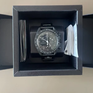 Swatch x Omega MoonSwatch “New Moon” – Snoopy Edition - Säljer den eftertraktade svarta Snoopy MoonSwatch “New Moon”, en hyllning till Omega Speedmasters roll i NASA:s rymdhistoria. Klockan har månfaskomplikation med Snoopy, UV-tryck som lyser i mörker och originalförpackning med kvitto. Klockan har aldrig använts och är helt ny. Finns att hämta på Lidingö.