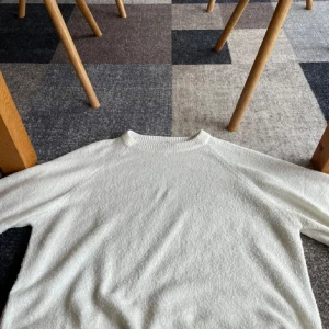 Vit stickad tröja från 157, storlek S - Mysig vit stickad tröja från 157 med rund halsringning och trekvartsärm. Tröjan har en enkel och clean look, perfekt att styla med jeans eller kjol. Materialet är mjukt och ger en avslappnad vibe.