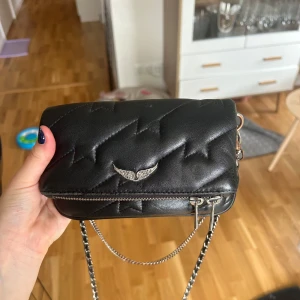 Zadig väska  - Säljer denna mini Zadig väskan. Köpt här på Plick. Använd men i fint skick, dock slitningar på färgen på ena silver kedjan. Inga slitningar i lädret och fin inuti! 