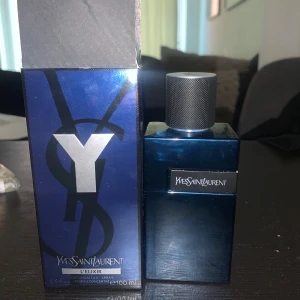 Yves Saint Laurent Y L'Elixir 100ml - Y L'Elixir från Yves Saint Laurent är en elegant herrparfym i en stilren, mörkblå glasflaska med svart och silverdetaljer. Flaskan rymmer 100 ml och har en robust, metallisk spraykork. Kommer i matchande blå kartong med stora YSL-loggan.