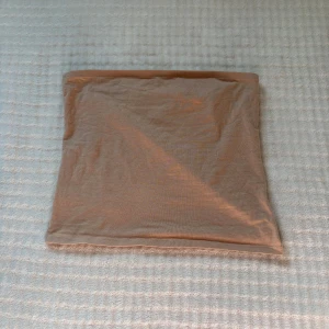 Beige tubtopp från H&M Divided - En enkel och stilren beige tubtopp från H&M Divided. Toppen är axelbandslös och har en rak, klassisk bandeau-form. Perfekt att matcha med jeans eller kjol för en clean look. Tillverkad i mjuk bomull som känns skön mot huden.