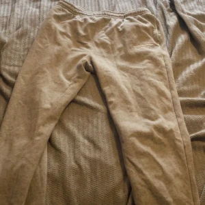 Grå mjukisbyxor från Swedemount - Grå mjukisbyxor från Swedemount med broderad logga på höften. Byxorna har resår i midjan och är gjorda i mjukt bomullsmaterial. Perfekta för chill eller träning, med enkel och clean look.