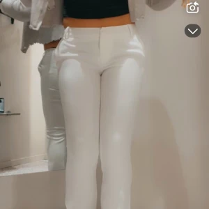Lågmidjade Vita kostymbyxor med bootcut - Snygga vita kostymbyxor med bootcut-snitt och låg midja. Byxorna har klassiska fickor fram, bälteshällor och stängs med dragkedja och knapp. Perfekta för en clean och stilren look. Materialet är slätt och känns bekvämt mot huden. Använd 1 gång.