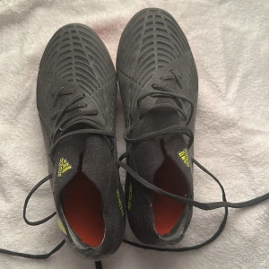 Adidas Predator svarta fotbollsskor - Säljer ett par Adidas Predator fotbollsskor i svart med gula detaljer och röda dobbar. Skorna har en modern design med mönstrad ovandel och klassiska tre ränder på sidan. Perfekta för dig som vill ha grymt grepp och stil på planen. Använda ungefär 4 gånger. Väldigt bra skick, pris kan diskuteras. Köpte dom för ungefär 2800kr men eftersom att jag växte ur dom så väljer jag nu att sälja dom. Fråga om mer bilder om de behövs 