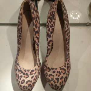 Leopardmönstrade pumps från Bianco st 37 - Snygga pumps från Bianco i leopardmönstrad mocka-look med rund tå och hög svart klack. Skorna har en röd plattform som ger extra attityd och sticker ut. Perfekta för dig som vill ha ett statement-piece till outfiten.