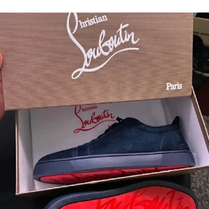 Mörkblå mocka sneakers från Louboutin (prisförslag) - Exklusiva mörkblå sneakers från Christian Louboutin i mocka med klassisk röd sula. Skorna har snörning, rund tå och diskret broderad logga baktill. Perfekta för dig som vill sticka ut med en lyxig och stilren look.storlek 47 