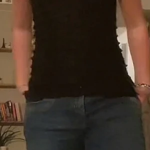 Svart linnetopp med volangdetaljer - Säljer en svart linnetopp med smala axelband och flera lager volangdetaljer som ger en cool och lekfull look. Toppen har en lätt glittrig finish och är perfekt för dig som vill sticka ut lite extra. Passar snyggt till både jeans och kjol.