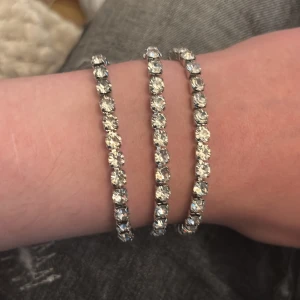 3 Glittriga tennisarmband i silverfärg - Tre stilrena tennisarmband med gnistrande stenar i silverfärg. Armbanden har klassisk design med runda, klara stenar som sitter tätt i rad och ger en lyxig känsla. Perfekta för att addera lite extra bling till din look. Det är inte samma som dem andra på bilderna så jag droppar alla 3 för 125kr eftersom det är inte samma kvalité 