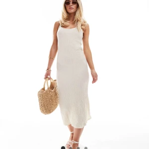 Krämvit texturerad klänning från Vila - Supersnygg krämvit långklänning från Vila med texturerat tyg och smala axelband. Klänningen har en slits bak, perfekt för varma dagar och somriga vibes. Helt ny och oanvänd.