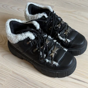 Chunky svarta platform skor - Svarta chunky platforms från koi footwear med vit fuskpäls runt kanten och coola metall-detaljer med dödskallar på snörningen. Grov plattformsula och snörning framtill. Knappt använda! Storlek 39, och dom är i jätte bra skick 