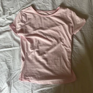 Ljusrosa t-shirt från SHEIN - En basic ljusrosa t-shirt från SHEIN med rund halsringning och korta ärmar. Modellen är enkel och har en figurnära passform, perfekt att matcha med jeans eller kjol. Tillverkad i mjuk bomull för en skön känsla hela dagen.