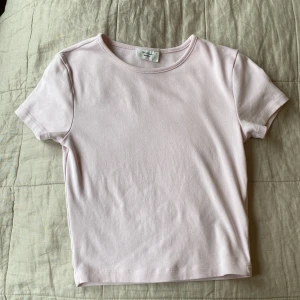 Ljusrosa basic t-shirt Gina Tricot - Enkel och stilren ljusrosa t-shirt från Gina Tricot, basically basics-kollektionen. T-shirten har rund halsringning, korta ärmar och är i en kortare modell. Nästan aldrig använd. Hade en pytteliten fläck på baksidan vid kragen men borde gå bort med lågor medel i tvätten