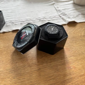 Svart G-Shock klocka från Casio - Säljer en svart G-Shock klocka från Casio med digital och analog display. Klockan har robust design, tydliga vita markeringar och skyddande boett. Armbandet är i syntetmaterial och spännet i metall. Perfekt för dig som gillar sportig och tålig stil. Den är i super bra kondition. 
