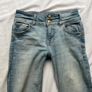 Ljusblå jeans från Bershka, strl 34 - Snygga ljusblå jeans från Bershka med klassisk femficksdesign och dubbla guldiga knappar i midjan. bootcut jeans med tajt passform ❤️