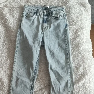 Ljusblå raka jeans i denim  - Säljer ett par ljusblå jeans med klassisk femficksdesign och raka ben. Jeansen har hög midja och är tillverkade i mjuk denim. Perfekta för en avslappnad och trendig look. är stretchiga 