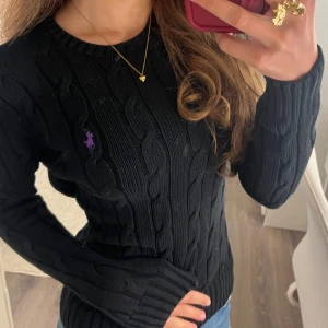  Ralph Lauren stickad tröja - Kabelstickad svart tröja från Polo Ralph Lauren med lila broderad logga på bröstet. Skriv för fler frågor💗