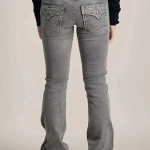 Grå bootcut jeans med fickdetaljer - Snygga grå jeans med bootcut passform och med detaljer på fickorna. Använd endast några gånger. Säljer pågrund av att den inte passar längre. Priset går att diskuteras.