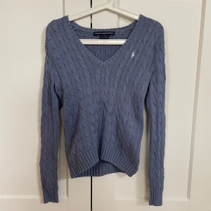 Blå kabelstickad tröja Ralph Lauren - Kabelstickad blå tröja från Ralph Lauren Sport i 100% bomull. V-ringad modell med lång ärm och broderad logga på bröstet. Liten i storleken så motsvarar mer storlek S. Tröjan är i mycket skick💕
