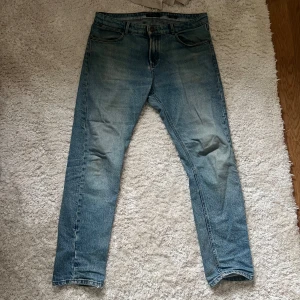 Blå jeans med slim fit  - Snygga blå jeans med klassisk femficksdesign och lätt tvättad look. Jeansen har en tapered passform som smalnar av nedtill och är tillverkade i slitstarkt denimtyg. Perfekta för en avslappnad och trendig stil. FRAKT BETALAR KÖPAREN