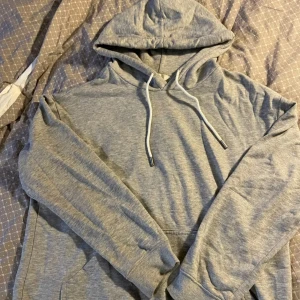 Grå hoodie från H&M - Säljer en klassisk grå hoodie från H&M i storlek S. Den har en justerbar huva med dragsko och en praktisk magficka. Perfekt för en avslappnad stil. 