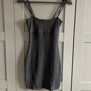 Svart miniklänning - Kort svart klänning med smala dubbla axelband och en liten slits framtill. I storlek XS från H&M.