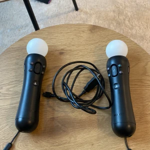 PlayStation Move Motion Controllers - Säljer två PlayStation Move Motion Controllers med sfäriska ljuskulor och knappar för en interaktiv spelupplevelse. Perfekt för VR-spel och kompatibla med PlayStation-konsoler. Inkluderar USB-kabel för laddning. Perfekt för att ta ditt spelande till nästa nivå!