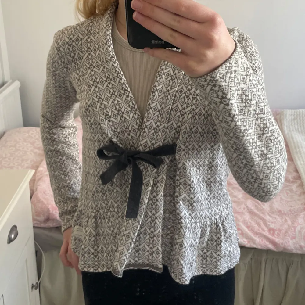 Säljer en snygg mönstrad kofta från Odd Molly i beige och brun. Koftan har ett fint mönster och knyts med ett svart band framtill. Perfekt för att ge din outfit en unik touch.. Neuletakit & Villapaidat.
