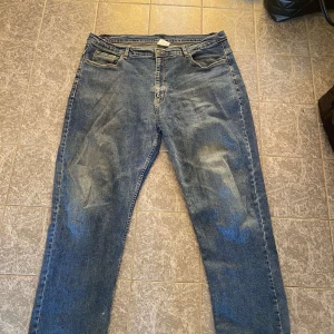 Blå jeansbyxor - Säljer ett par klassiska blå jeansbyxor med en rak passform. De har en traditionell femficksdesign och en knappgylf. Slitage vid ändarna och vänster ficka är söndrig.
