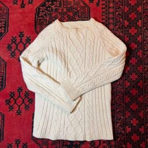 Vit stickad tröja - Säljer en stilren vit hemstickad tröja med kabelstickat mönster. Tröjan har långa ärmar och en klassisk rund halsringning. Perfekt för kyligare dagar.